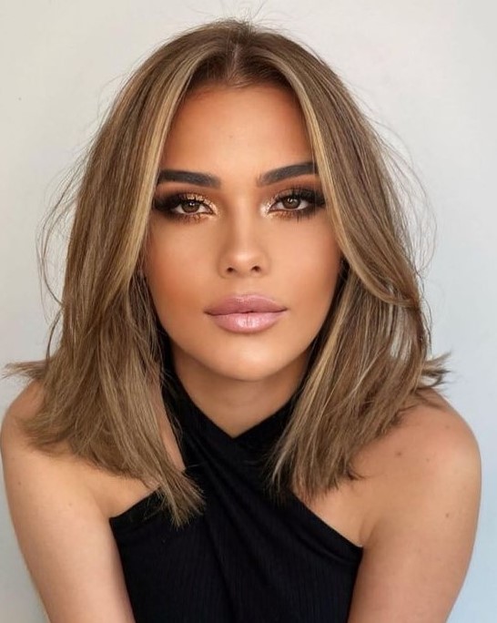 a soft brown outgrown bob with a bit of blonde highlights and soft curtain bangs dyed blonde, too