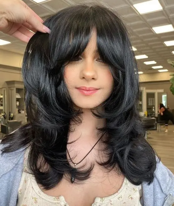 a medium black butterfly haircut with curtain bangs and curled ends and a shiny touch is amazing