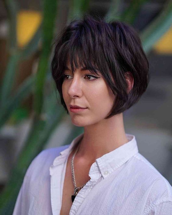 a black layered jaw-length bob with wispy bangs and shaggy layers looks very retro-inspired