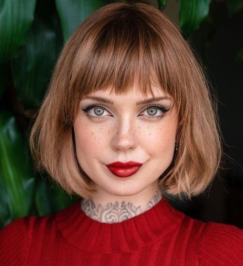 a brown reddish chin length bob with blunt textured bangs and curved ends is a lovely idea