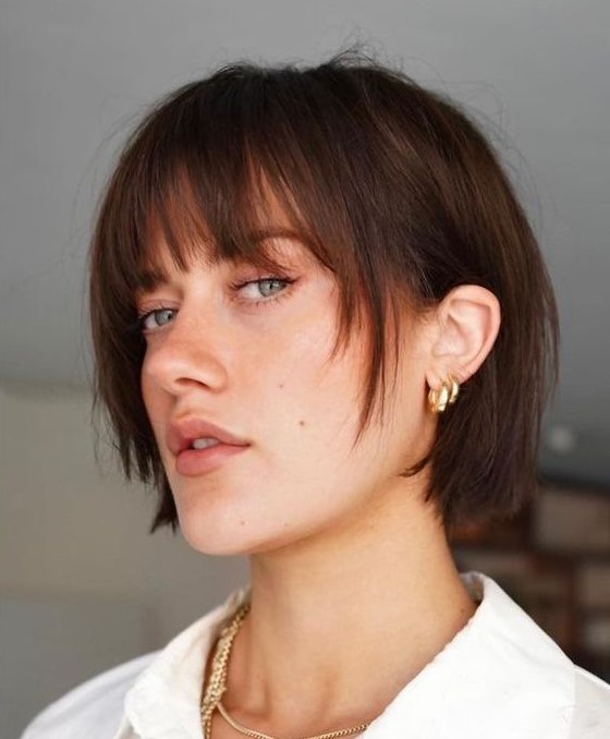 a blunt dark brunette bob with wispy bangs and face-framing layers is a catchy idea to try right now