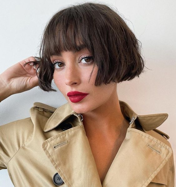 a chic dark brunette ear-length bob with a classic fringe and messy waves looks relaxed, cute and refined