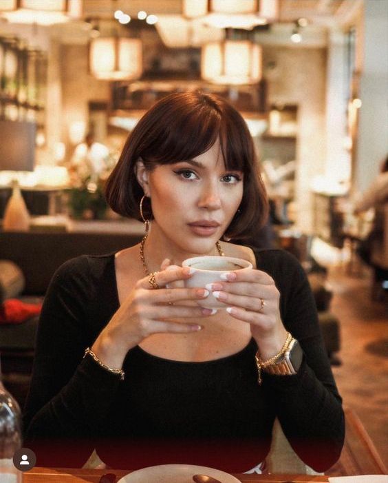 a dark brunette jaw-length bob with bottleneck bangs and rounded ends is a stylish and chic idea