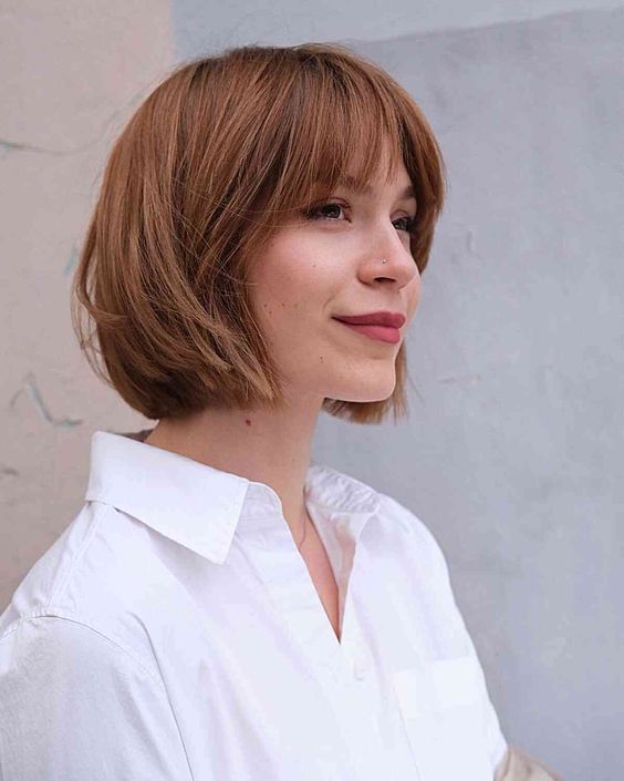 a ginger brunette choppy bob with wispy bangs and caramel balayage is a very stylish idea