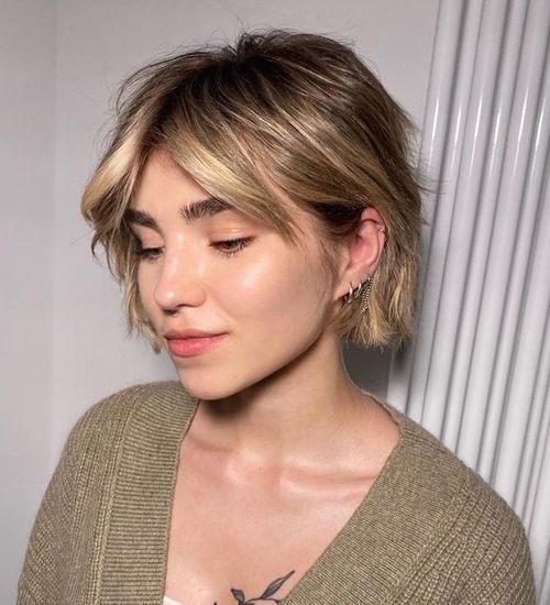 a messy and shaggy jaw-length bob with blonde balayage and short curtain bangs plus waves is a very fresh solution