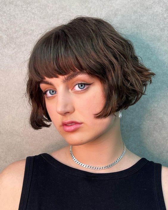 a short brunette bob with a classic fringe and messy waves is a retro-inspired and chic hairstyle