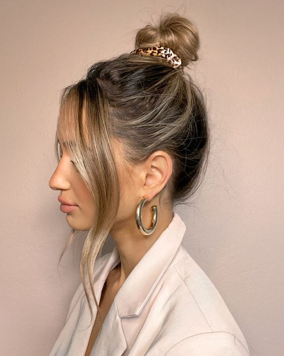 a messy top knot with a messy top and waves framing the face plus a leopard print scrunchie for an accent