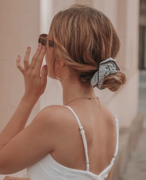 a messy and wavy low bun with a messy top and face-framing hair plus a printed scrunchie is cool