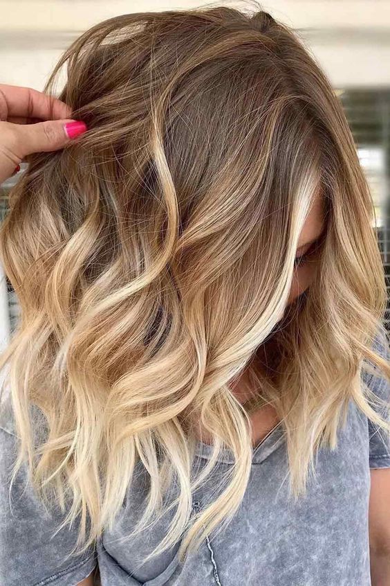 shoulder-length hair with an ombre effect from light brunette to bleached blonde and with waves