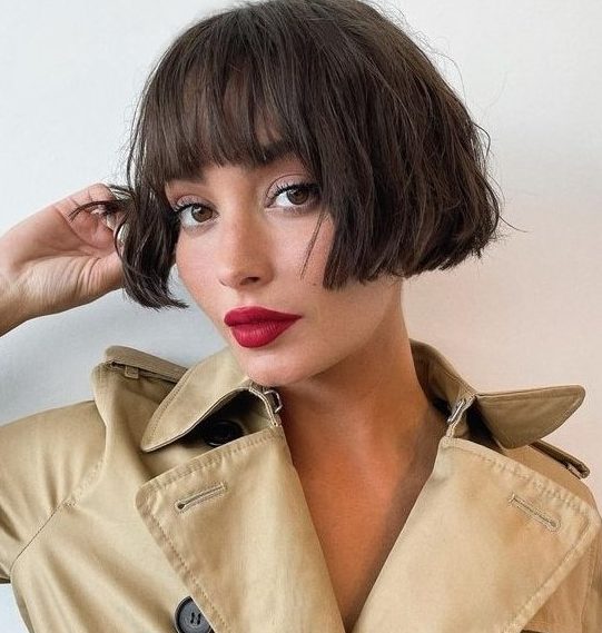 a chic dark brunette ear-length bob with a classic fringe and messy waves looks relaxed, cute and refined