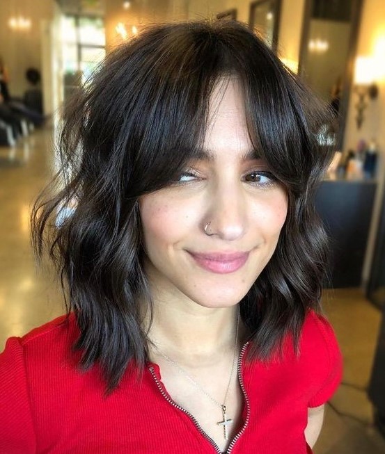 a dark brown shaggy long bob with messy waves and bottleneck bangs is a very chic and cool idea