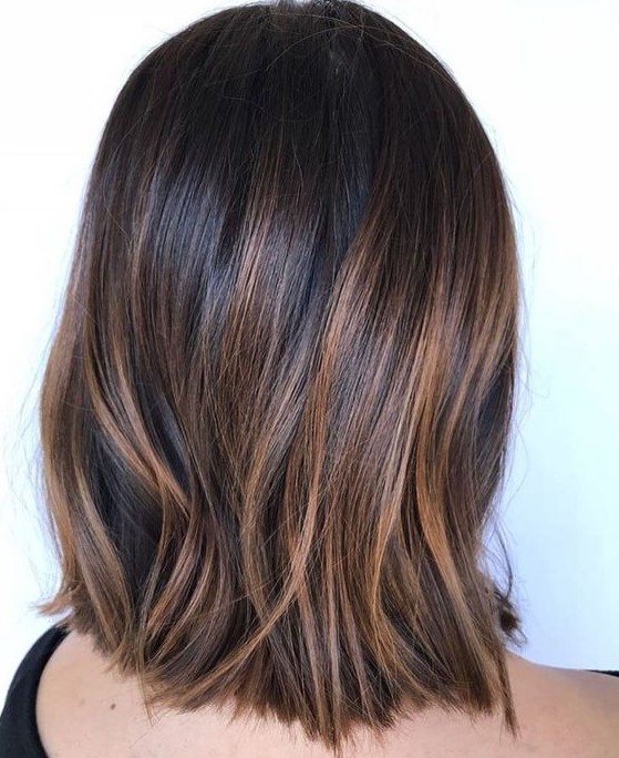 very dark brown straight long bob with delicate caramel highlights that add eye-catchiness and interest to the look