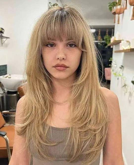 a buttefly haircut done on honey blonde hair with layered bangs and a lot of feathered layers is a chic and lovely idea