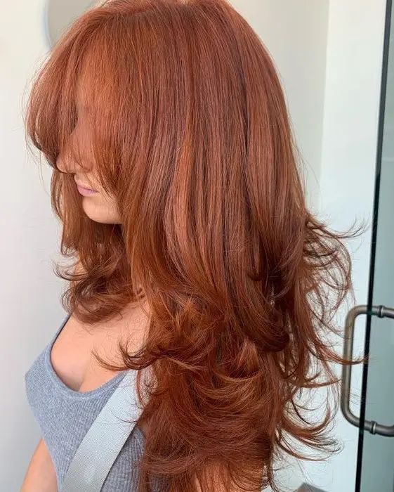 a breathtaking long red butterfly haircut with a lot of volume, wispy bangs and curled ends is a lovely idea