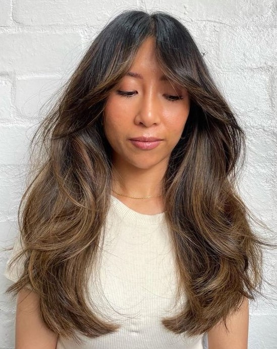 a long dark brunette haircut with bottleneck bangs, dimension and waves plus caramel balayage