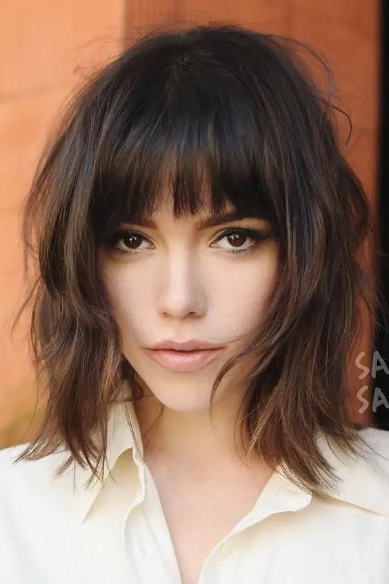 a lovely dark brown long shaggy bob with caramel highlights and a classic fringe plus messy waves is a cool and chic idea