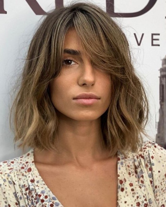 a messy bronde long bob with a darker root and waves plus curtain bangs to soft the look even more