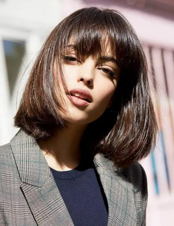 a shiny dark brown long bob with a classic fringe, with a lot of volume and curved ends is an elegant and timeless solution