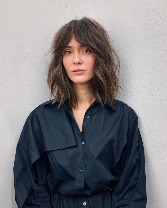 a long brown bob with slight highlights, messy waves and bottleneck bangs is a trendy solution to rock now