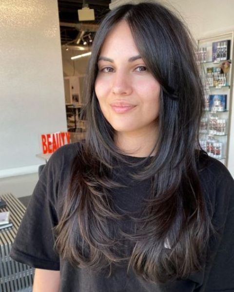 a long dark brunette butterfy haircut with curled ends and long curtain bangs is a lovely idea