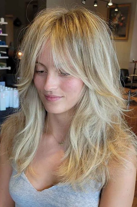 a gorgeous long blonde wolf haircut with curtain bottleneck bangs, messy waves down is a lovely hairstyle with much volume