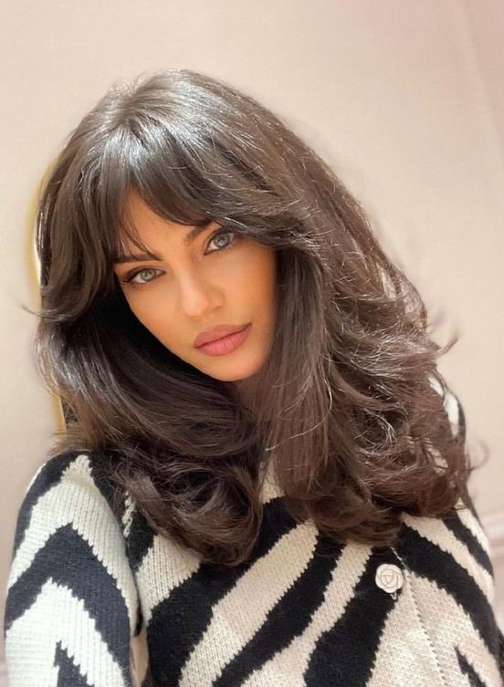 a dark brunette medium butterfly haircut on thick hair, with bottlneck bangs and waves is wow