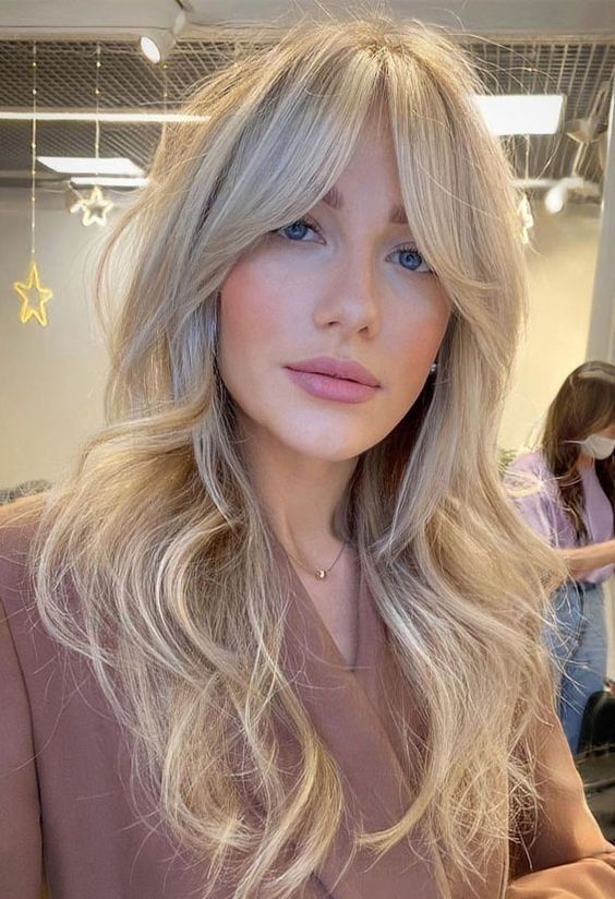 a long blonde butterfly haircut with curtain bangs and waves is a very lovely and delicate idea