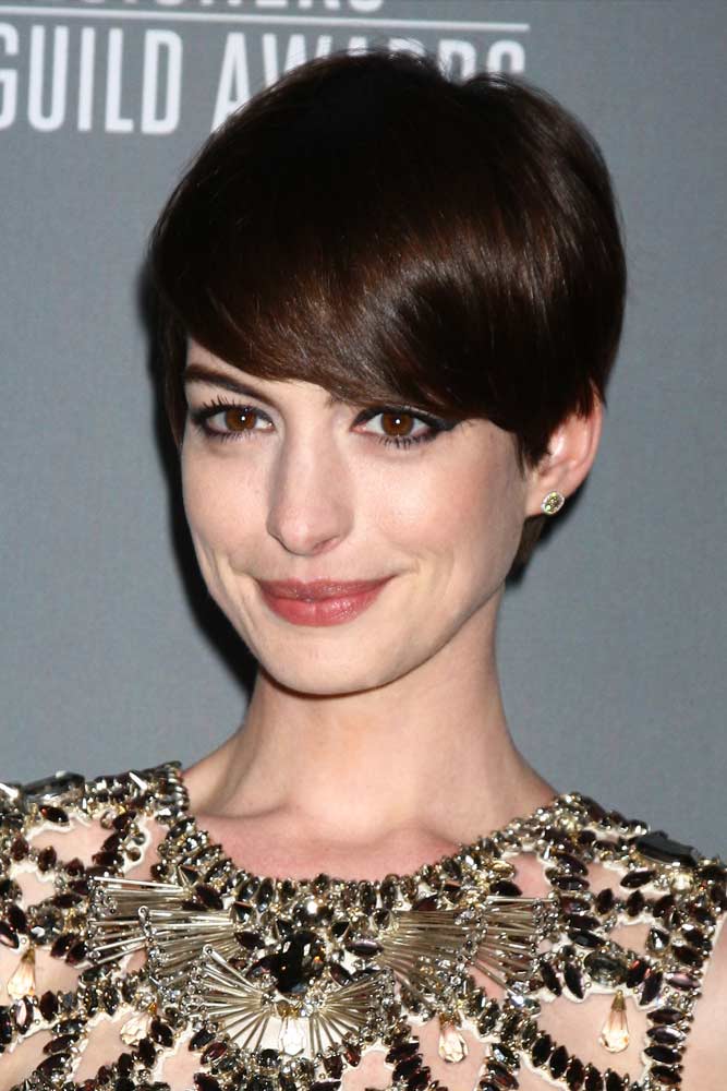 Anna Hathaway wearing a long dark brown pixie that emphasizes the beauty of the face farming it