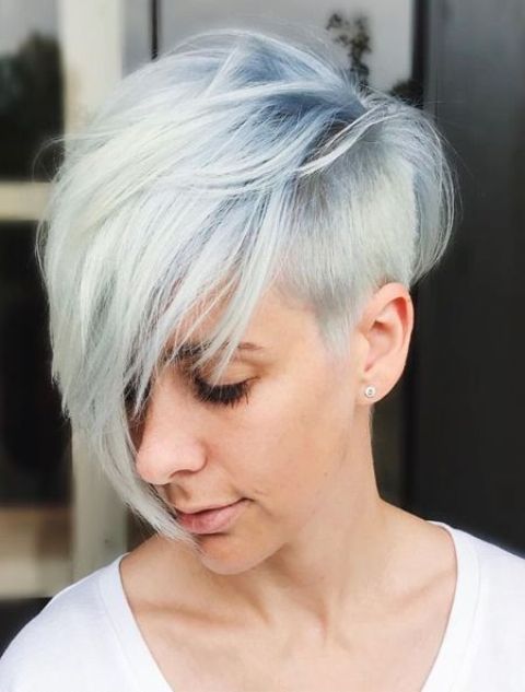 a longer pixie haircut with a side fringe and a chic blue to white balayage