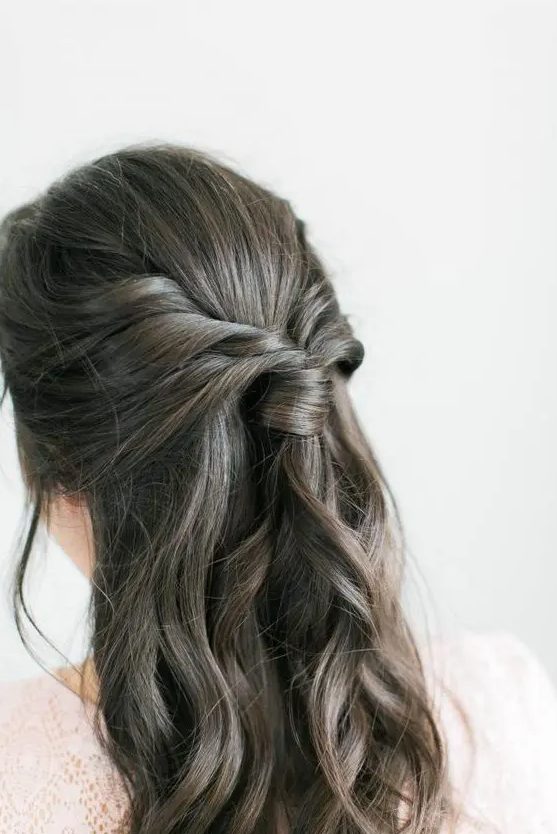 a boho half updo with a sleek top, a twisted ponytail and waves down is a lovely solution