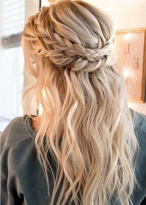 a romantic half updo with a double braided halo and waves plus bangs for parties