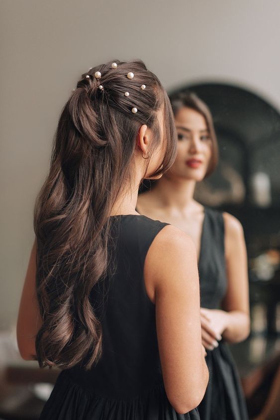 a gorgeous long half updo with a  ponytail, pearls on top and wavy hair down is a stylish and catchy idea