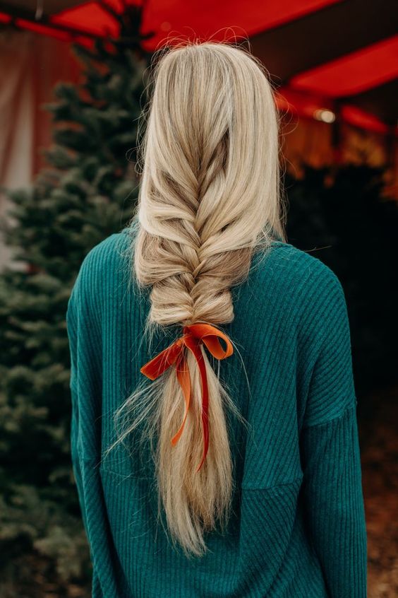 a long loose braid with an orange velvet bow is a cool hairstyle for Christmas, it looks relaxed and lovely