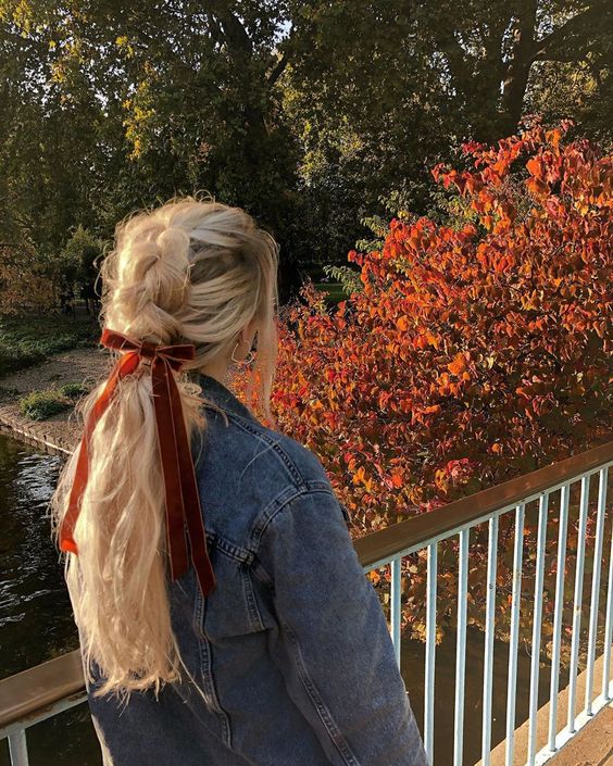 a lovely Christmassy chunky braid with waves down and a woven top plus a red velvet bow is a cool party hairstyle