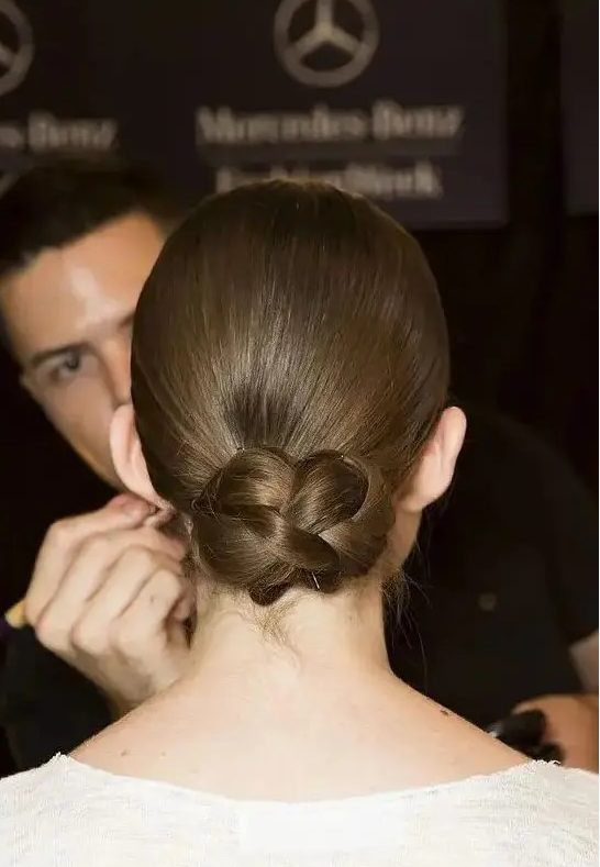 a sleek low updo with a braided bun is a cool and modern interpretation of a traditional low bun or chignon