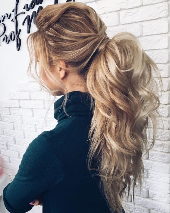 a luxurious messy and wavy ponytail with bangs and a large bump is a bold idea for long hair