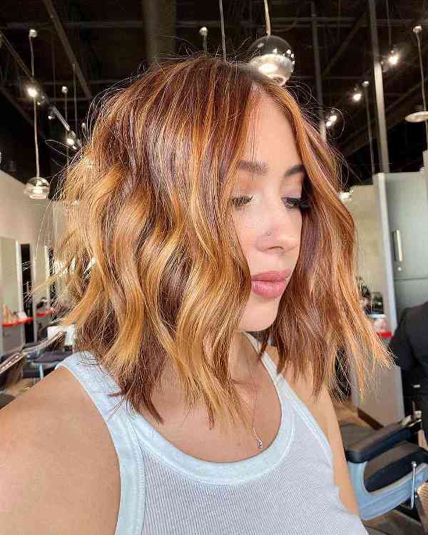 an auburn and orange wavy long bob with layers and a shiny finish is a super bold and catchy idea to try