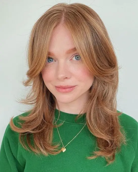 a ginger medium butterfly haircut with long curtain bangs and curled ends is a lovely solution