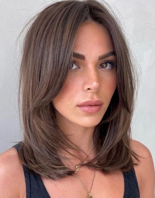 an elegant layered brunette haircut with curtain bangs and curled ends is a stylish idea to try right now