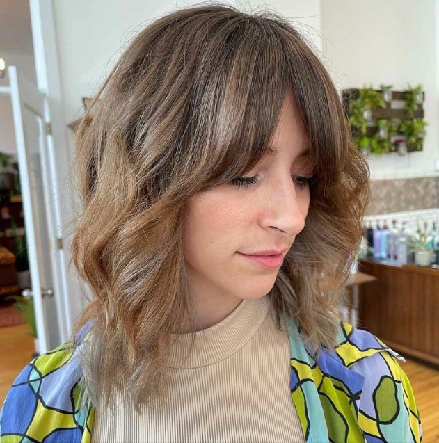 a light brown long wavy bob with curtain fringe and highlights is a cool hairstyle with minimum effort