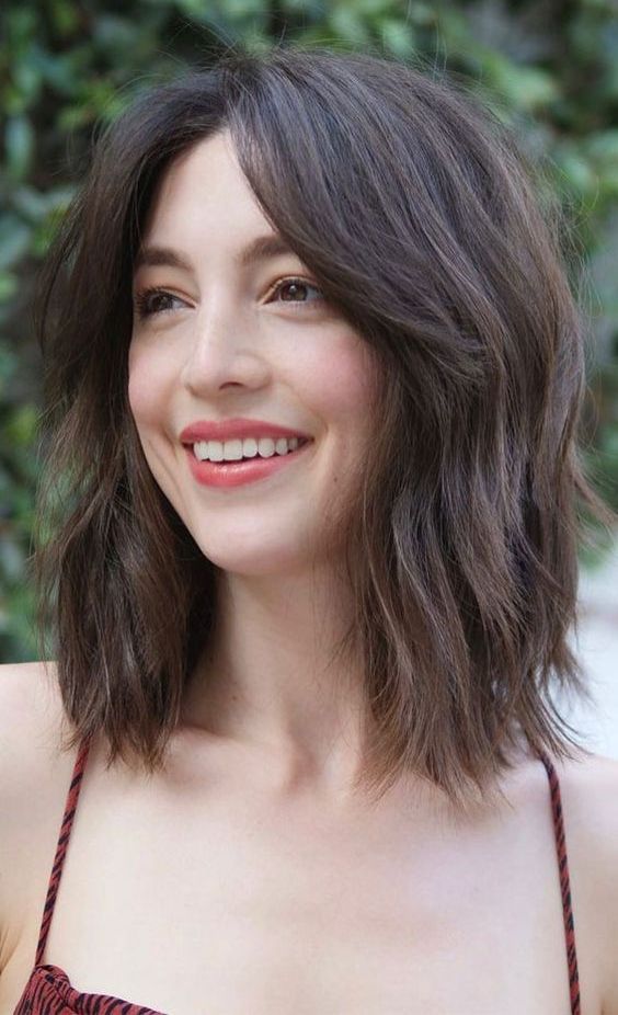 a brown layered long bob with curtain bangs and texture is a cool and chic idea for a lovely look