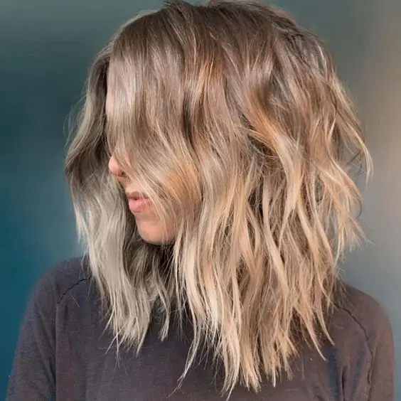 a beautiful beach bronde shaggy haircut with beach waves and central part looks very lovely and relaxed