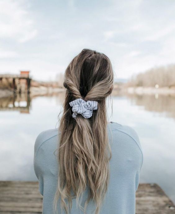 a simple half updo with a a twisted part and wavy hair down plus a striped scrunchie for every day